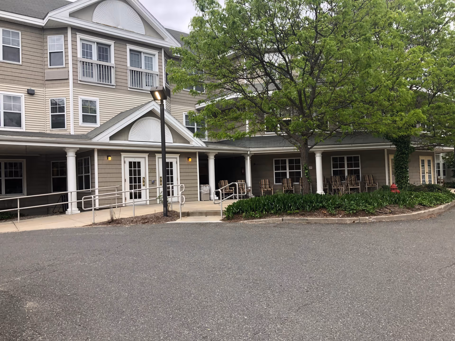Exterior view of a senior living facility with a covered entrance and outdoor seating.