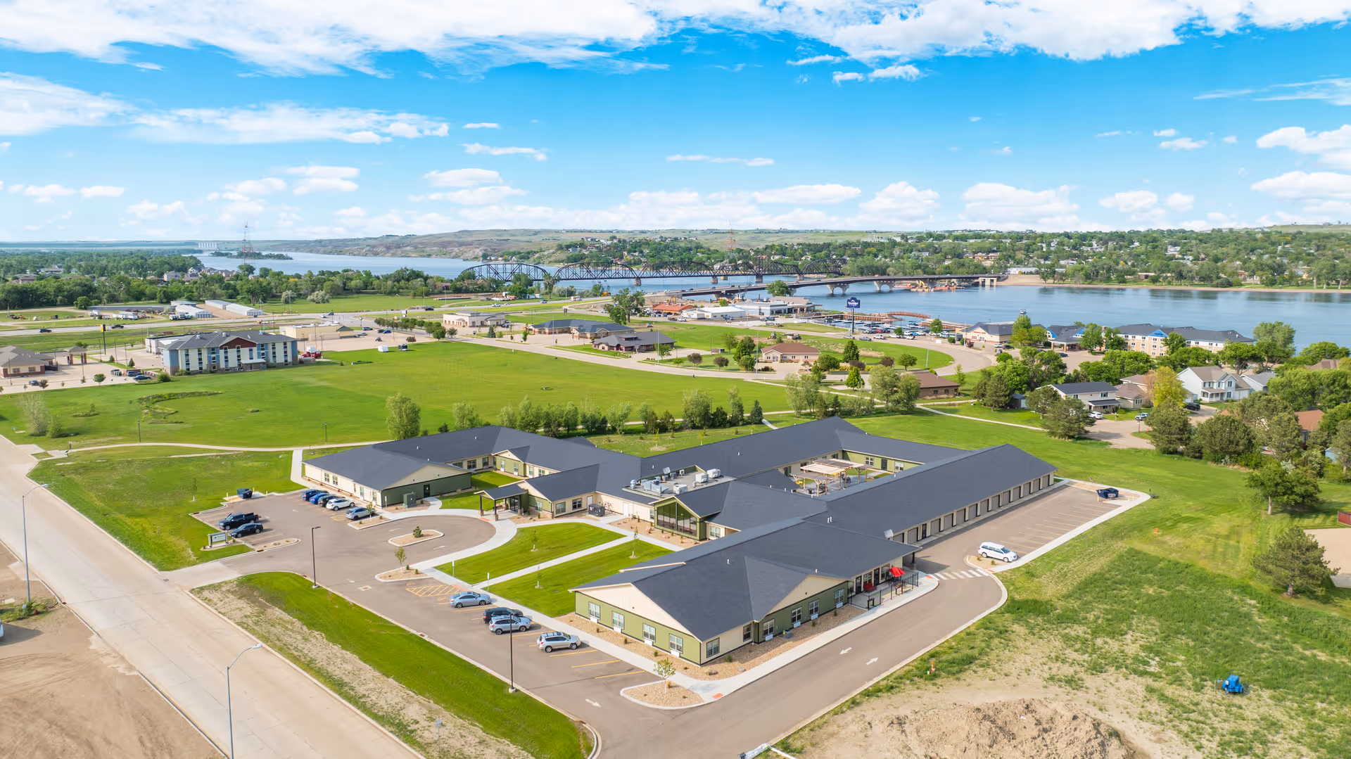 Aerial view of a multi-wing senior living campus by a river.