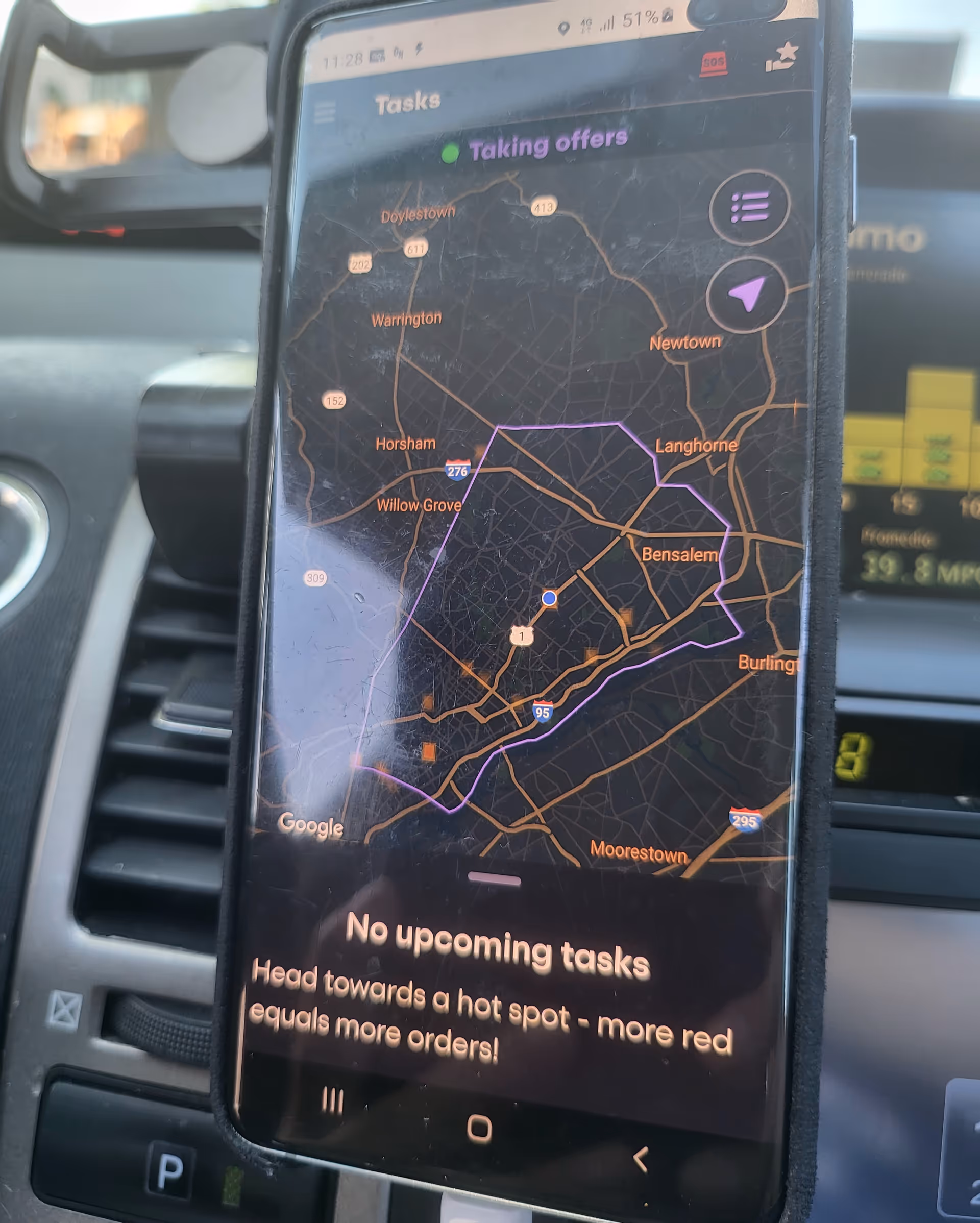 Close-up of a smartphone displaying a navigation map inside a car dashboard.