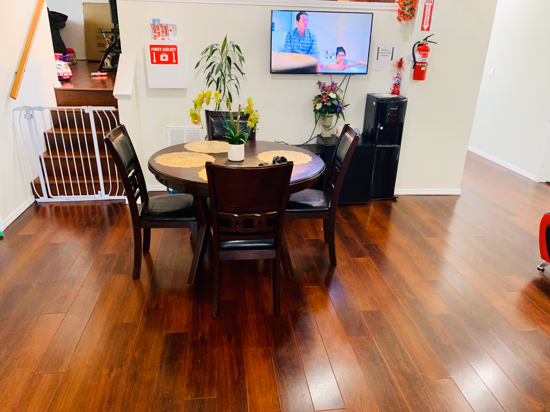 Round wooden dining table with four chairs in a bright dining area.