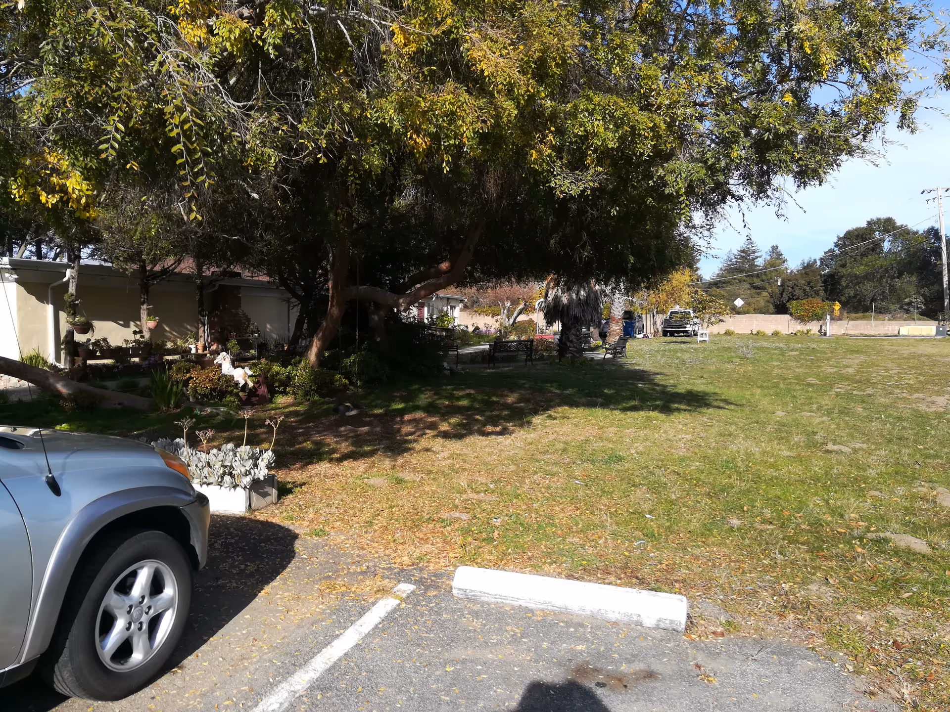 Outdoor view of a senior living facility exterior with a parked car and trees.