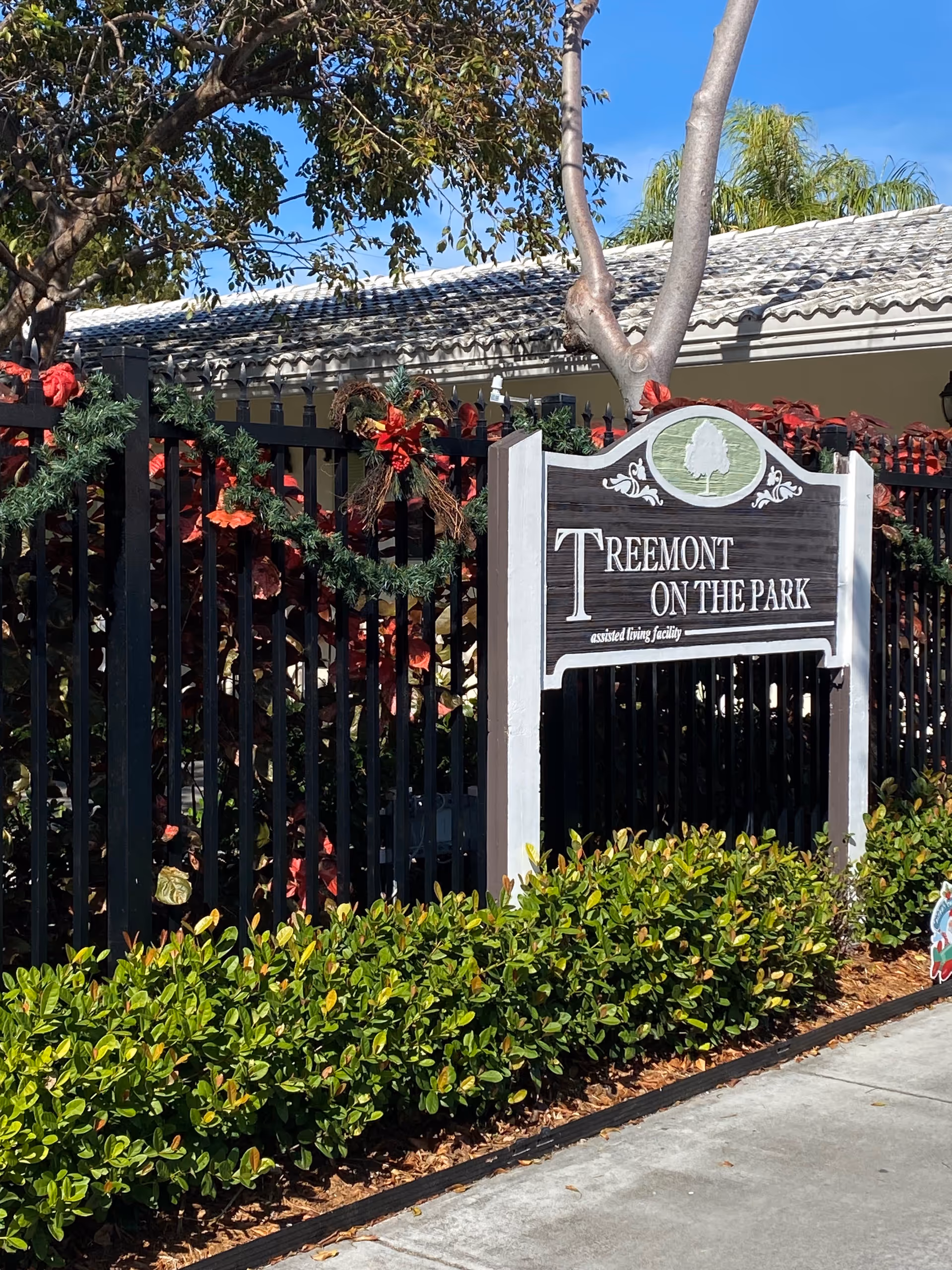 Exterior view of Treemont on the Park sign with fence and greenery.