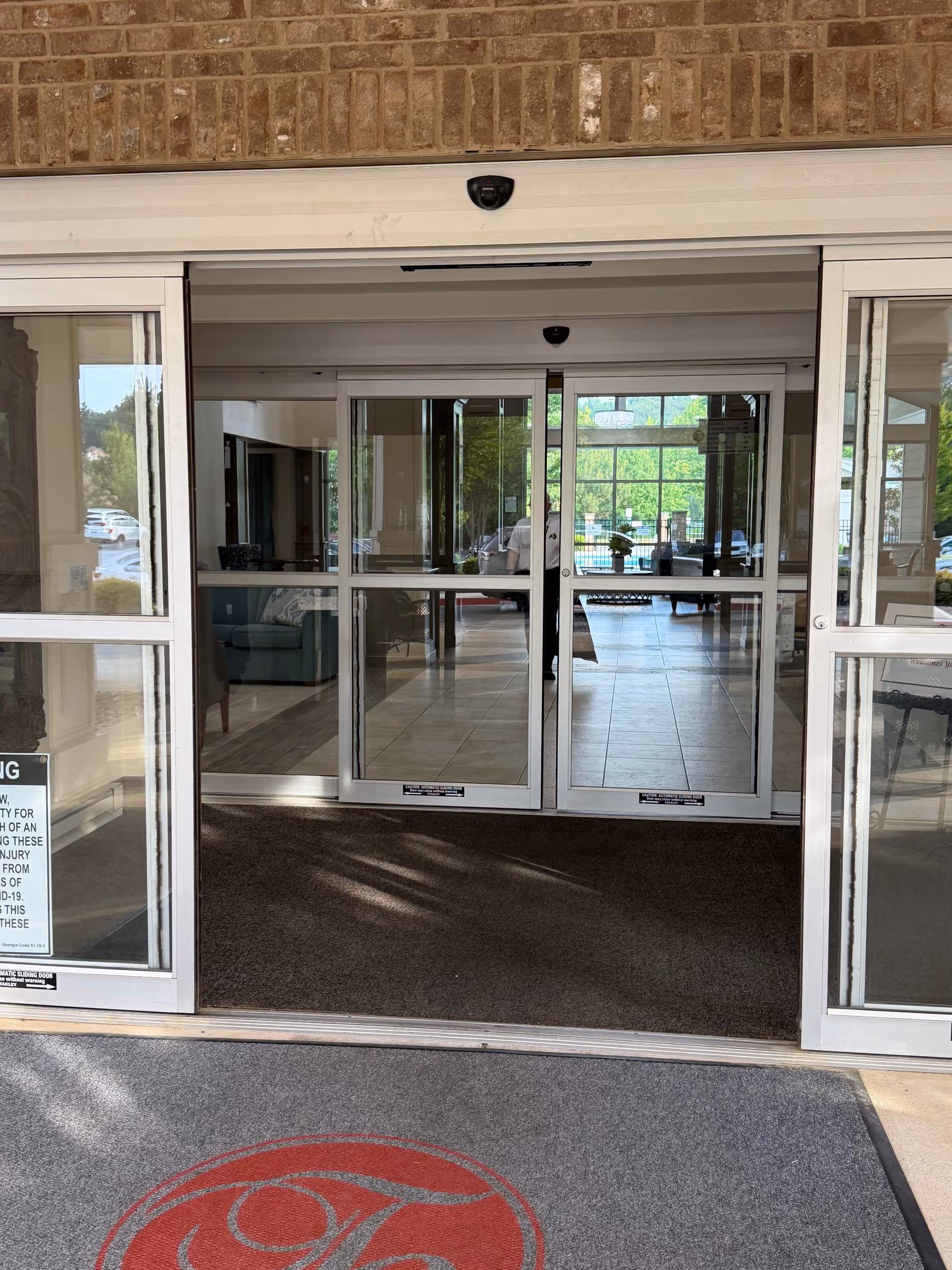 Front entrance with glass automatic doors opening into a bright lobby.