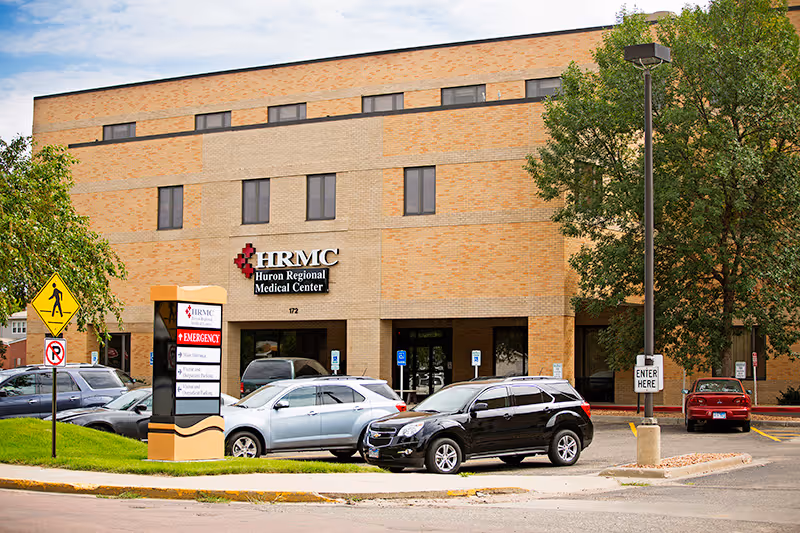 Exterior view of Huron Regional Medical Center with cars in the parking lot.