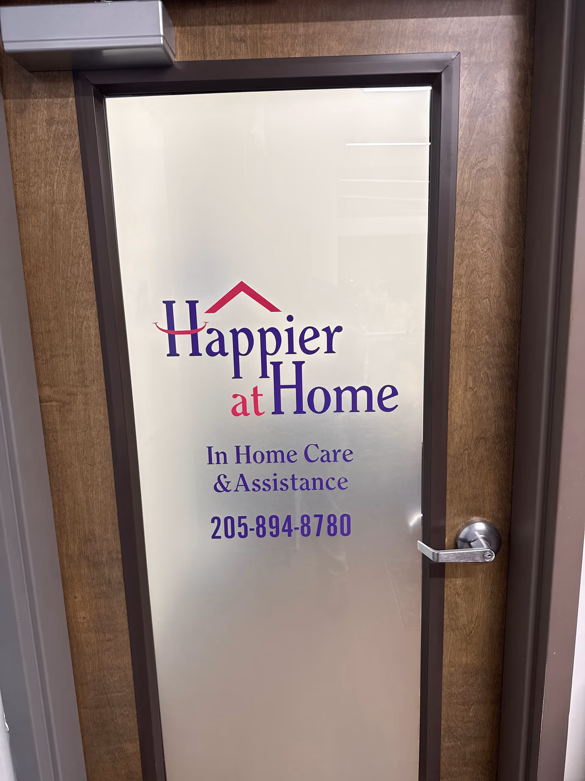 Framed glass door displays Happier at Home branding and contact information.