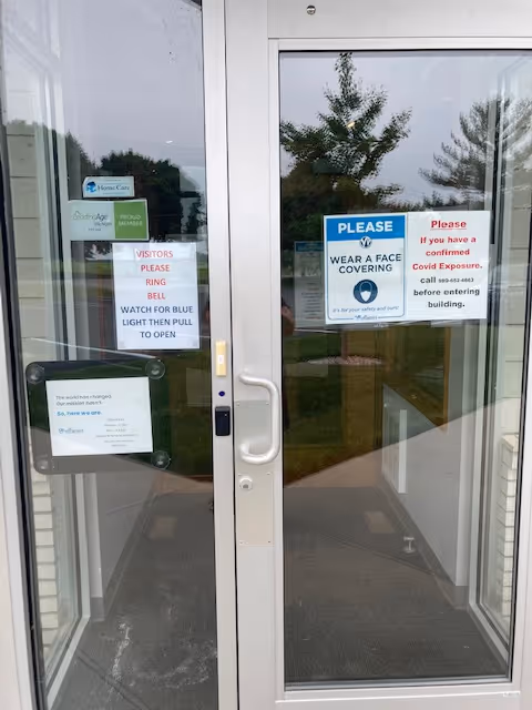 Glass entrance door with health notices and a face-covering sign posted