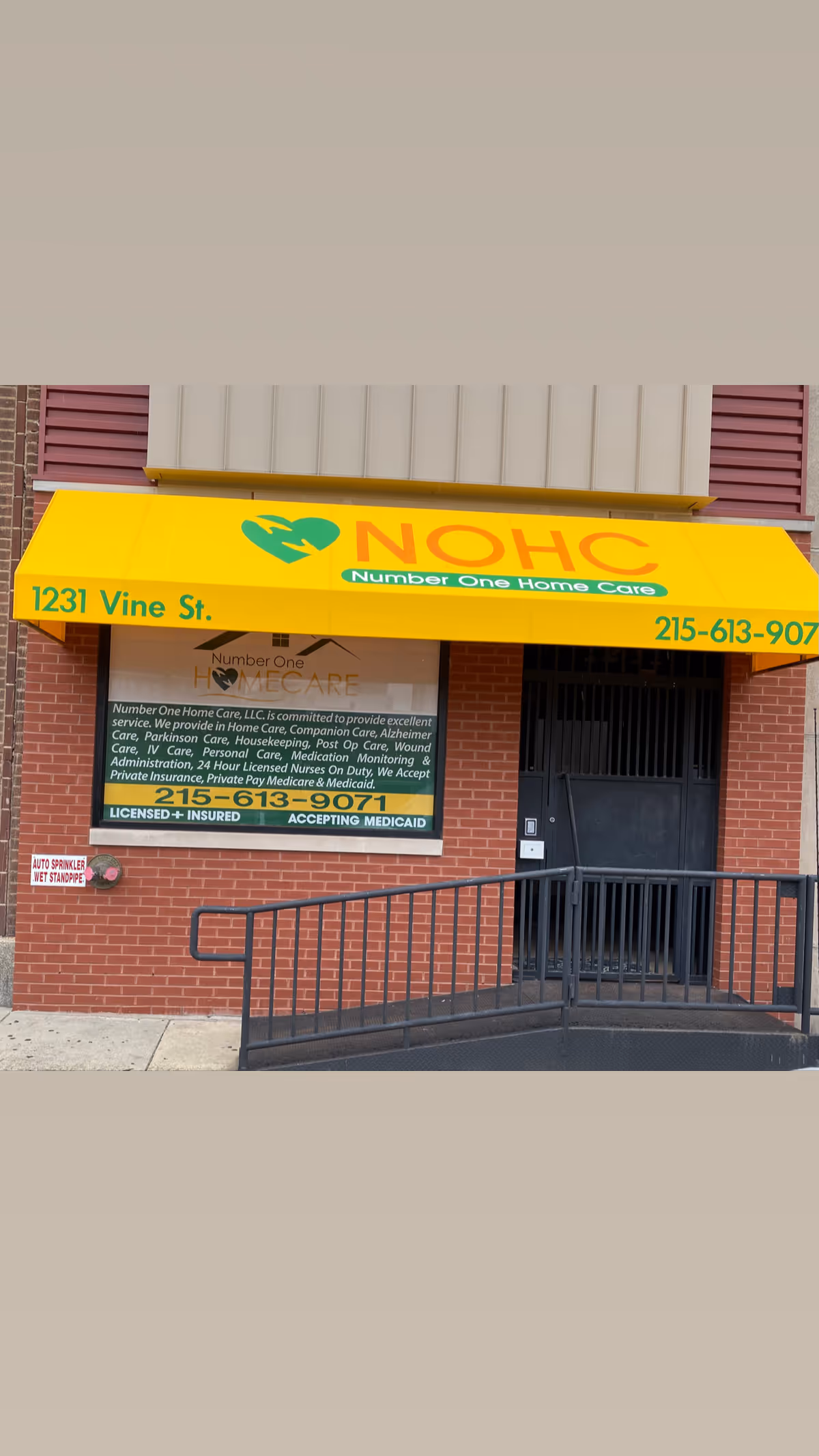 Brick building entrance with a yellow NOHO awning and ramp, Number One Home Care signage.