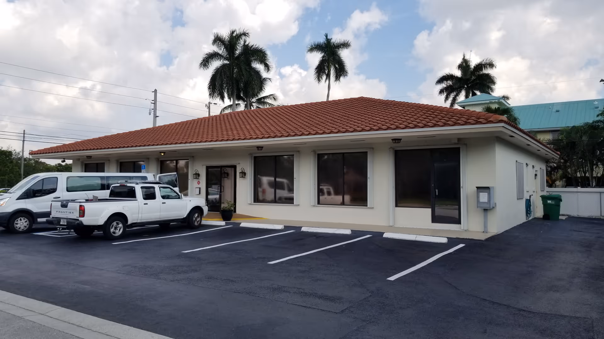 Exterior of TheKey Concierge Nursing (formerly Expicare) building with parking and palm trees.