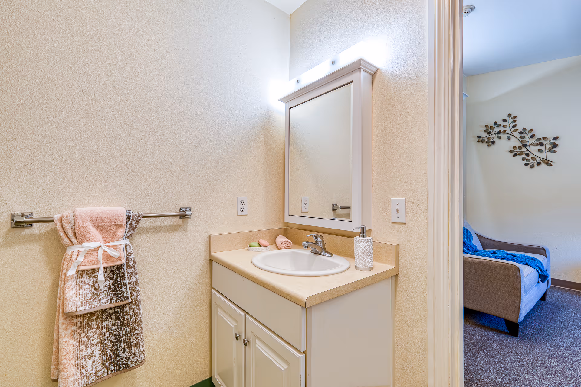 Bathroom vanity with sink, mirror, towel rack, and doorway to adjacent living area.