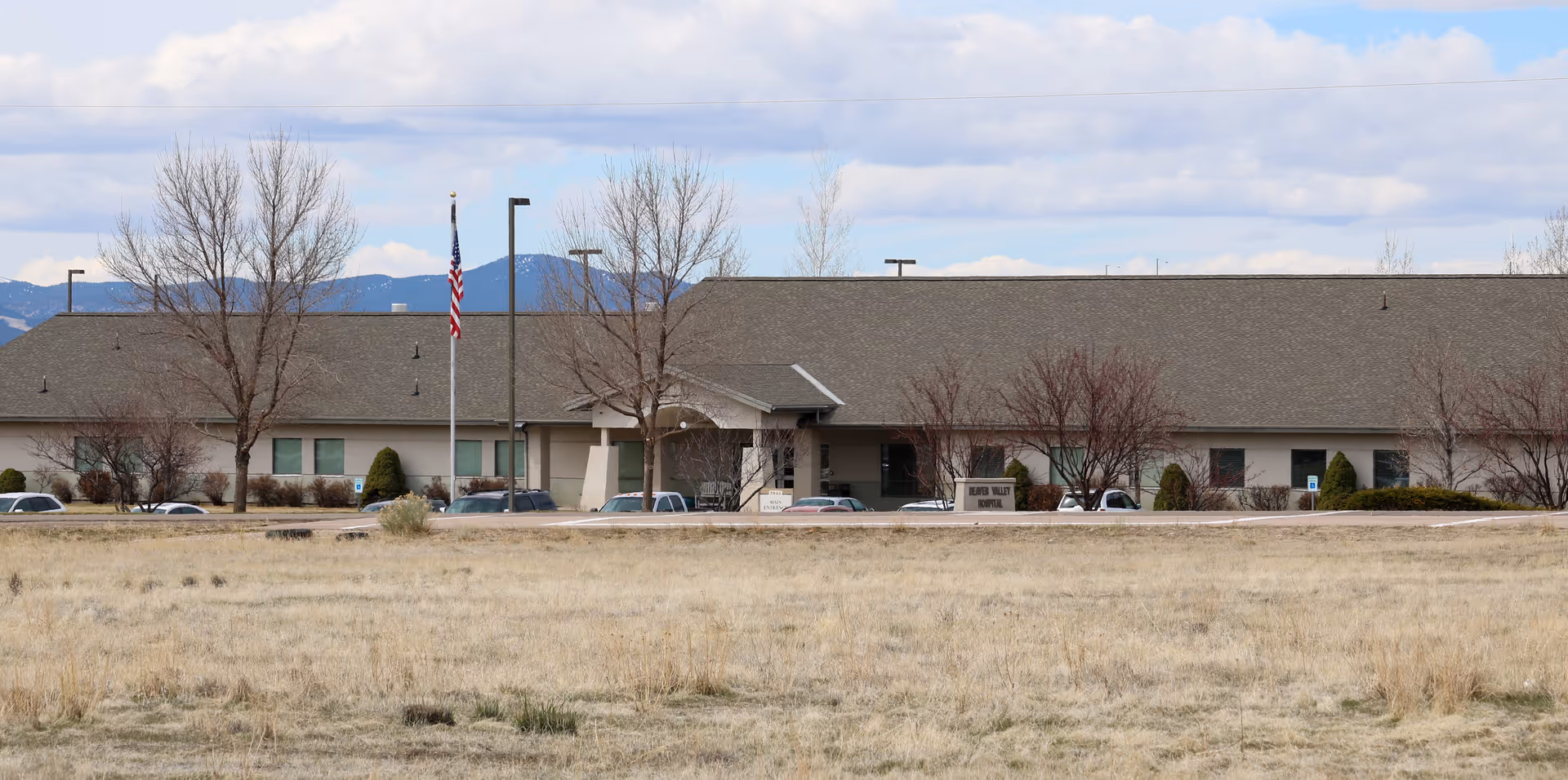 Beaver Valley Hospital front entrance with flagpole, parking, and leafless trees.