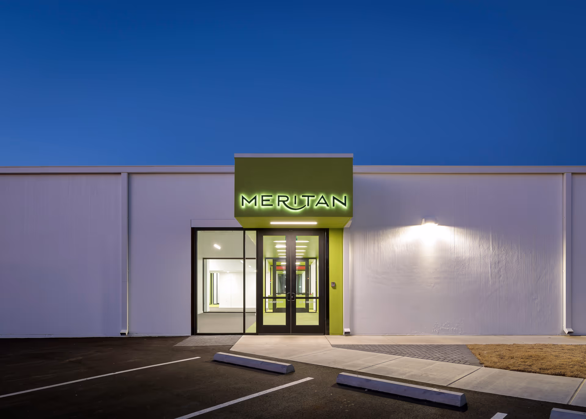 Exterior view of Meritan facility entrance with illuminated green sign.