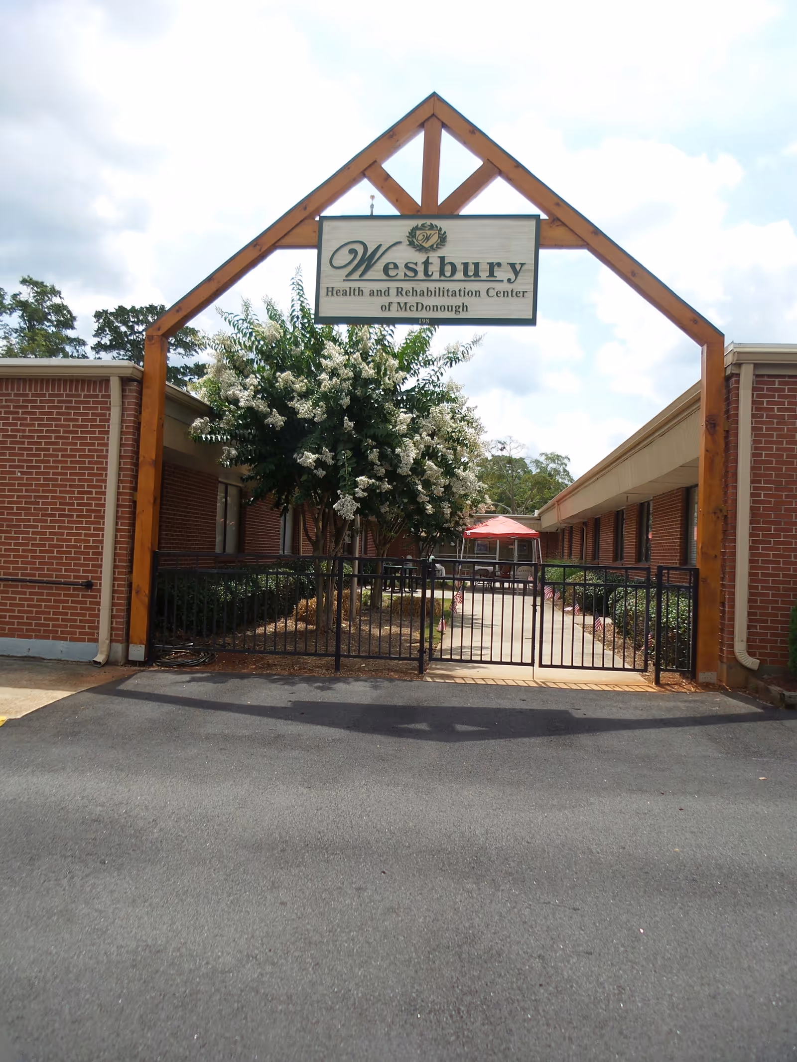 Brick facility entrance with wooden arch sign Westbury at McDonough.