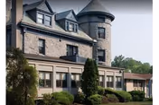 Stone-clad nursing facility with turreted tower and landscaped grounds.