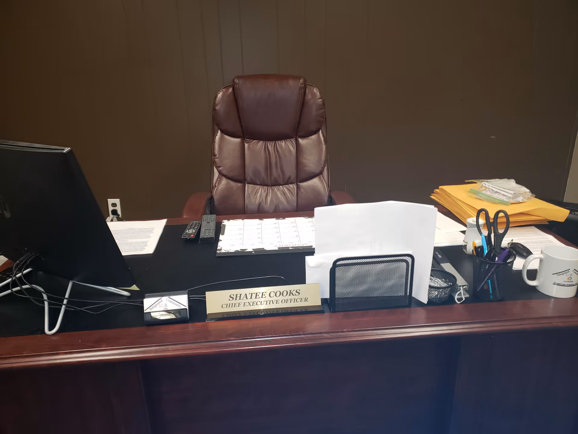 Executive desk with brown leather chair, paperwork, and a Chief Executive Officer nameplate.