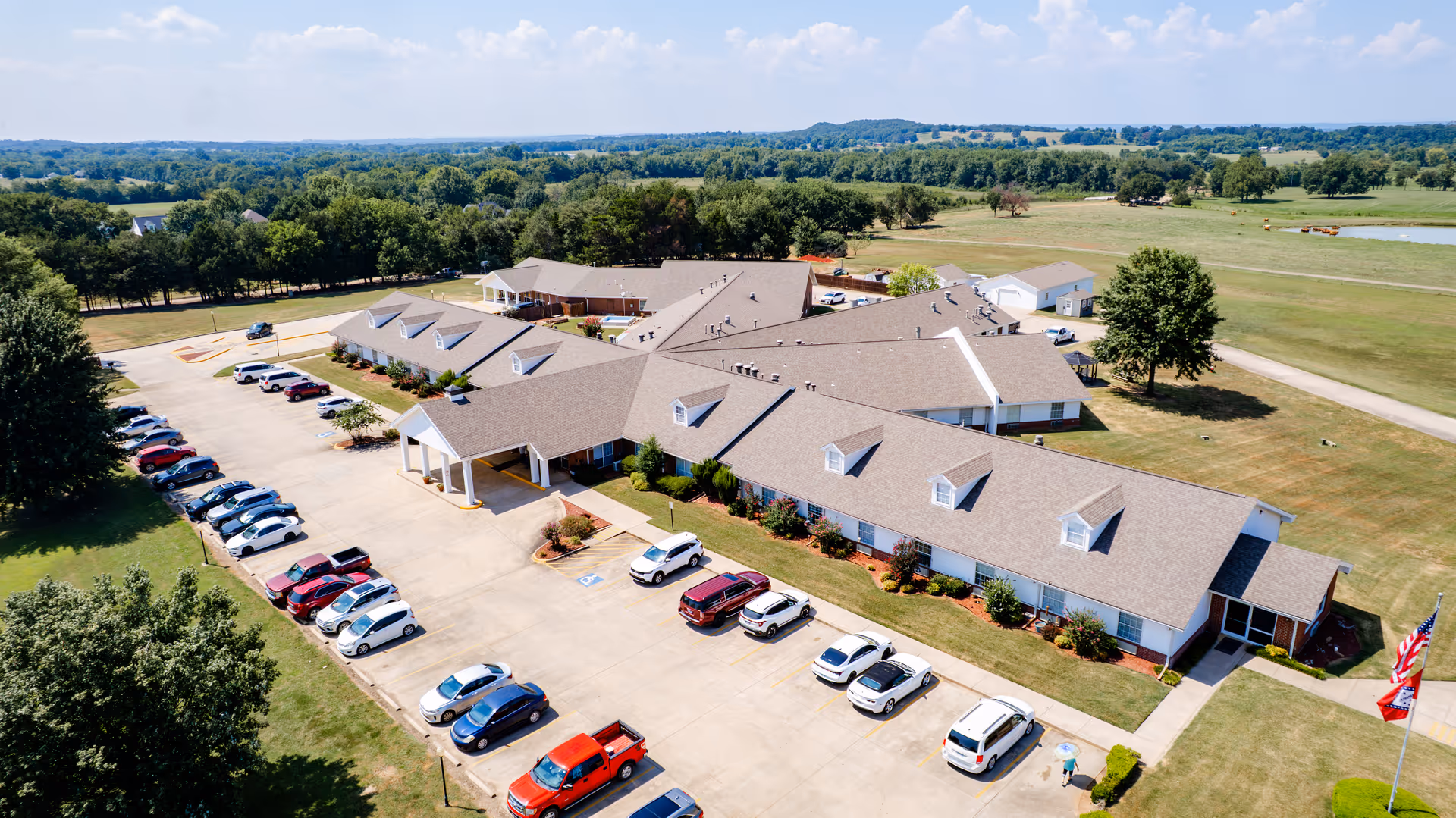 Aerial view of Greenhurst Nursing Center with parking and surrounding farmland.
