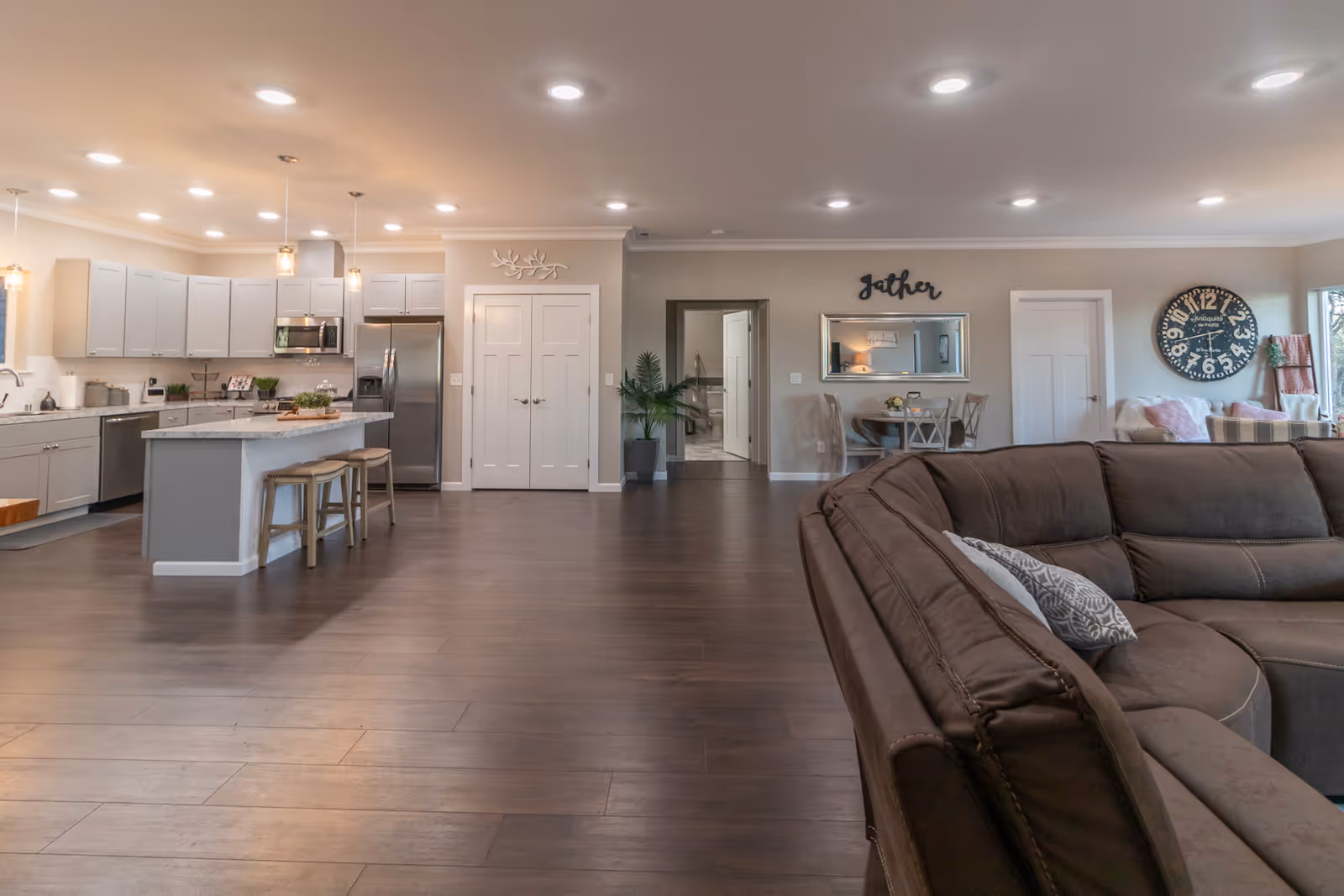Open-concept living area with kitchen island, stainless appliances, and brown sectional sofa.