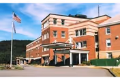 Brick senior care facility building with a covered entrance, flagpole, and driveway.