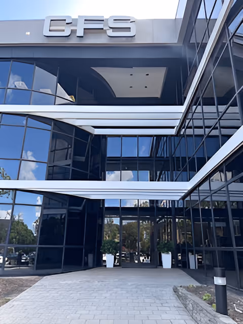 Front view of a modern glass building entrance with a paved walkway
