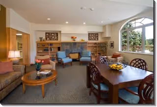 Bay Vista Commons cozy lounge with sofas, chairs, dining table, and arched window.