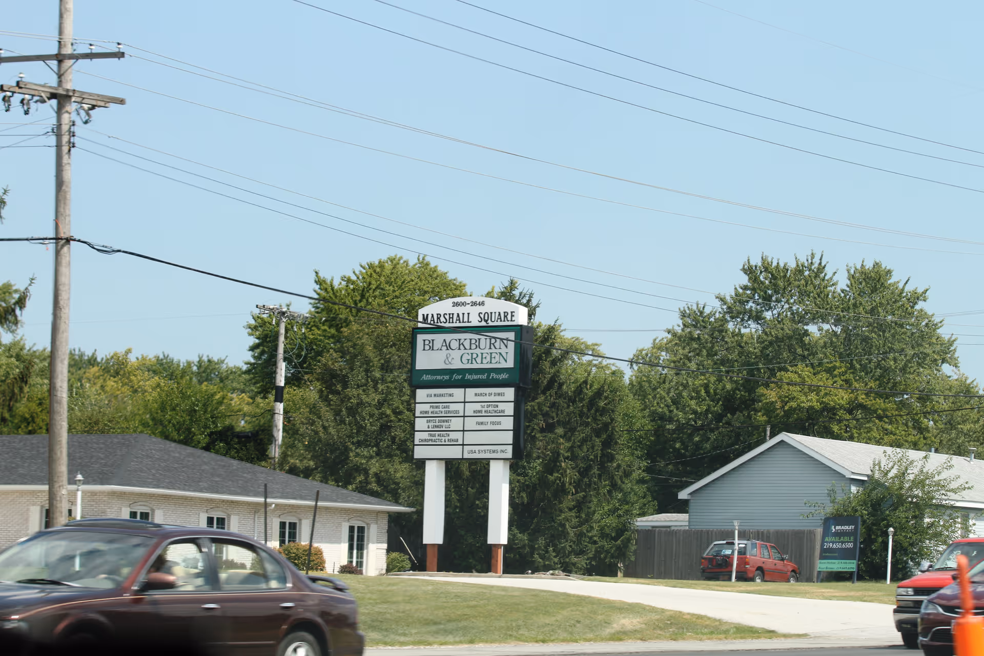 Outdoor street scene with a tall Marshall Square sign and nearby houses.