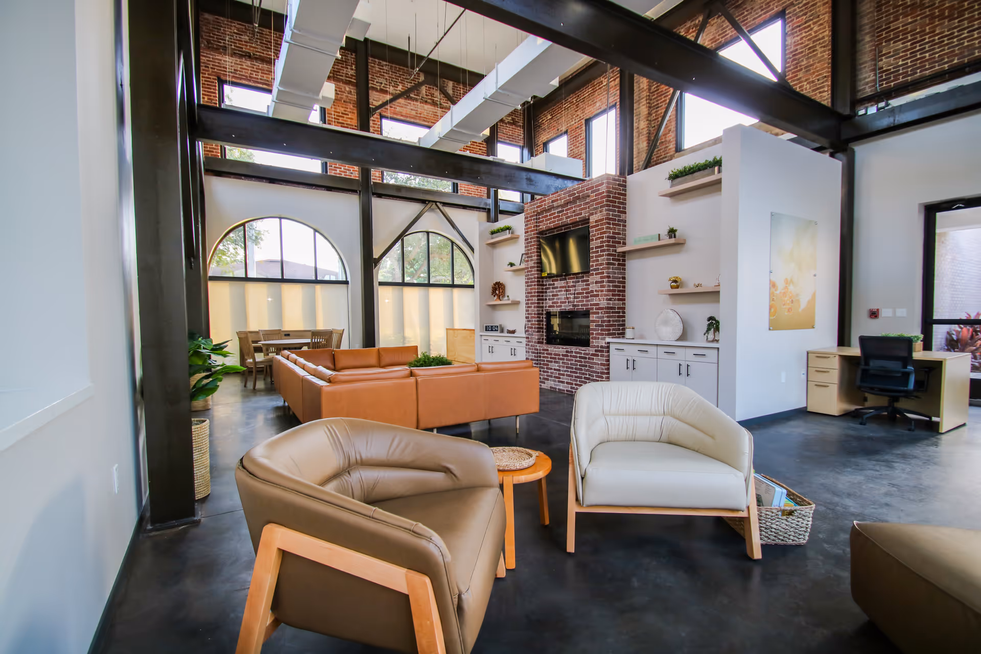 Spacious modern lounge with brick fireplace, sectional couches, and wall-mounted shelves.