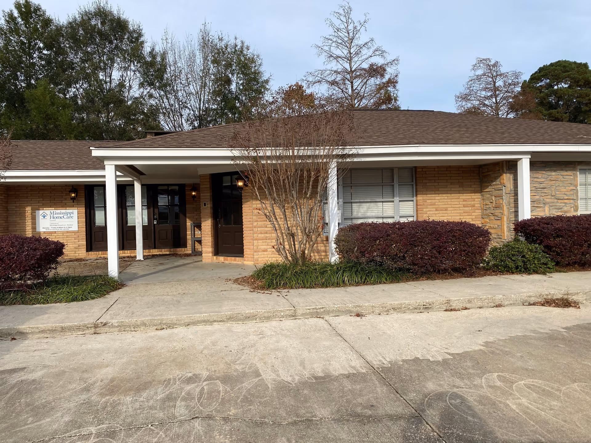 Front exterior of a single-story brick senior care facility with a covered entrance.