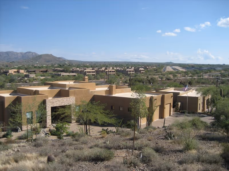Exterior view of a desert-toned senior living campus with low stucco buildings.