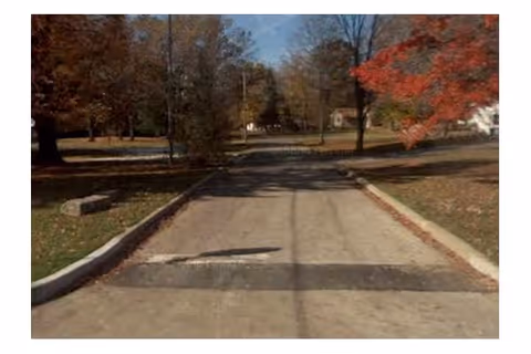 An outdoor paved path with fall-colored trees lining both sides.