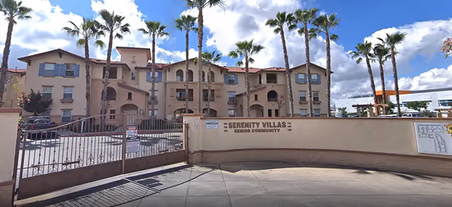 Front view of Serenity Villas Senior Community with gated entrance and palm trees