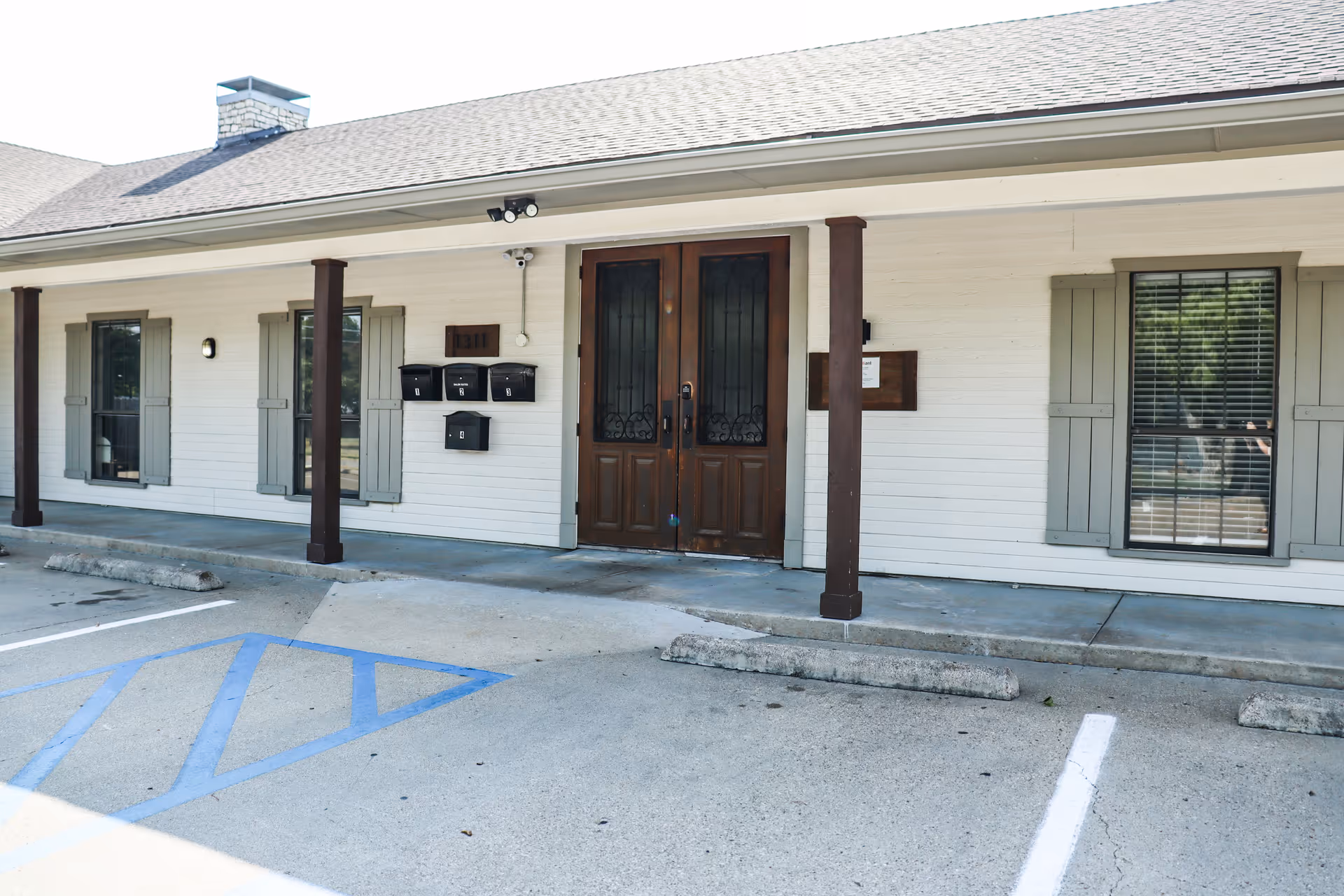 Front exterior of a white facility building with double wood doors and shutters.
