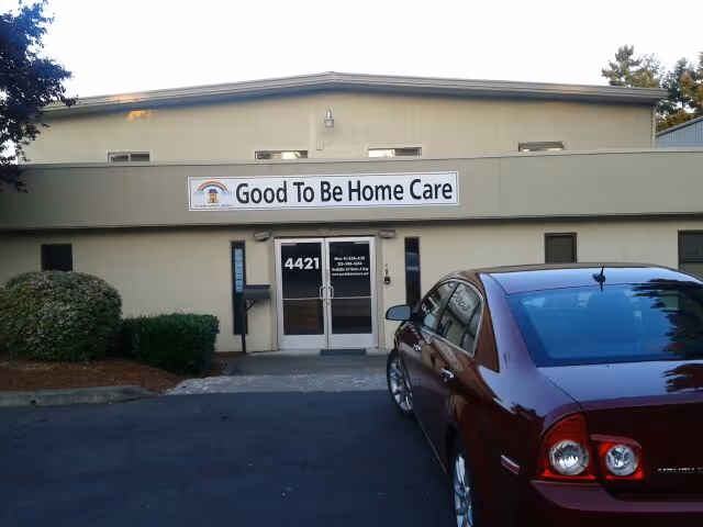Entrance to Good To Be Home Care facility with a maroon car parked outside.