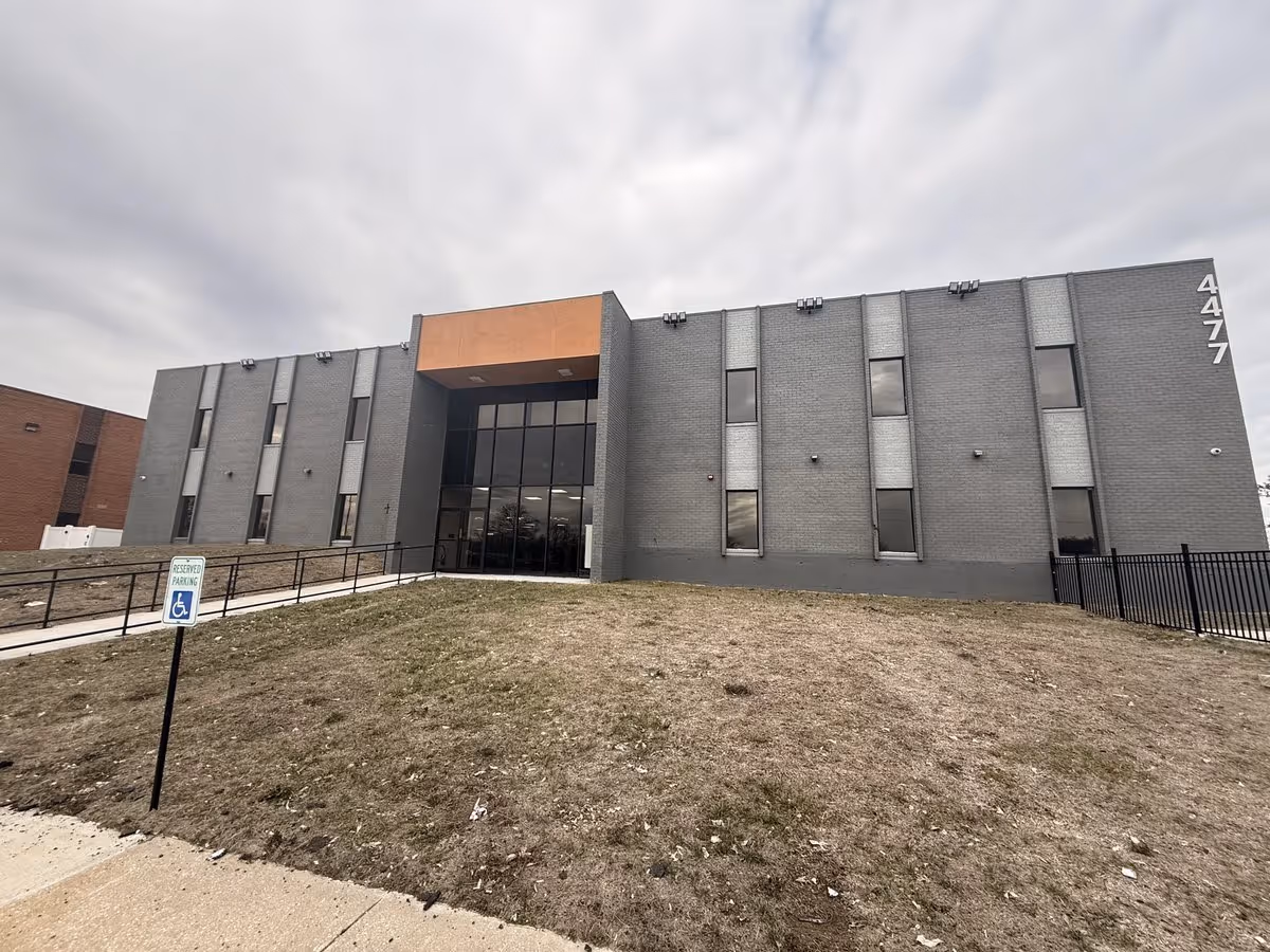 Front view of a gray brick senior living facility with glass entrance.