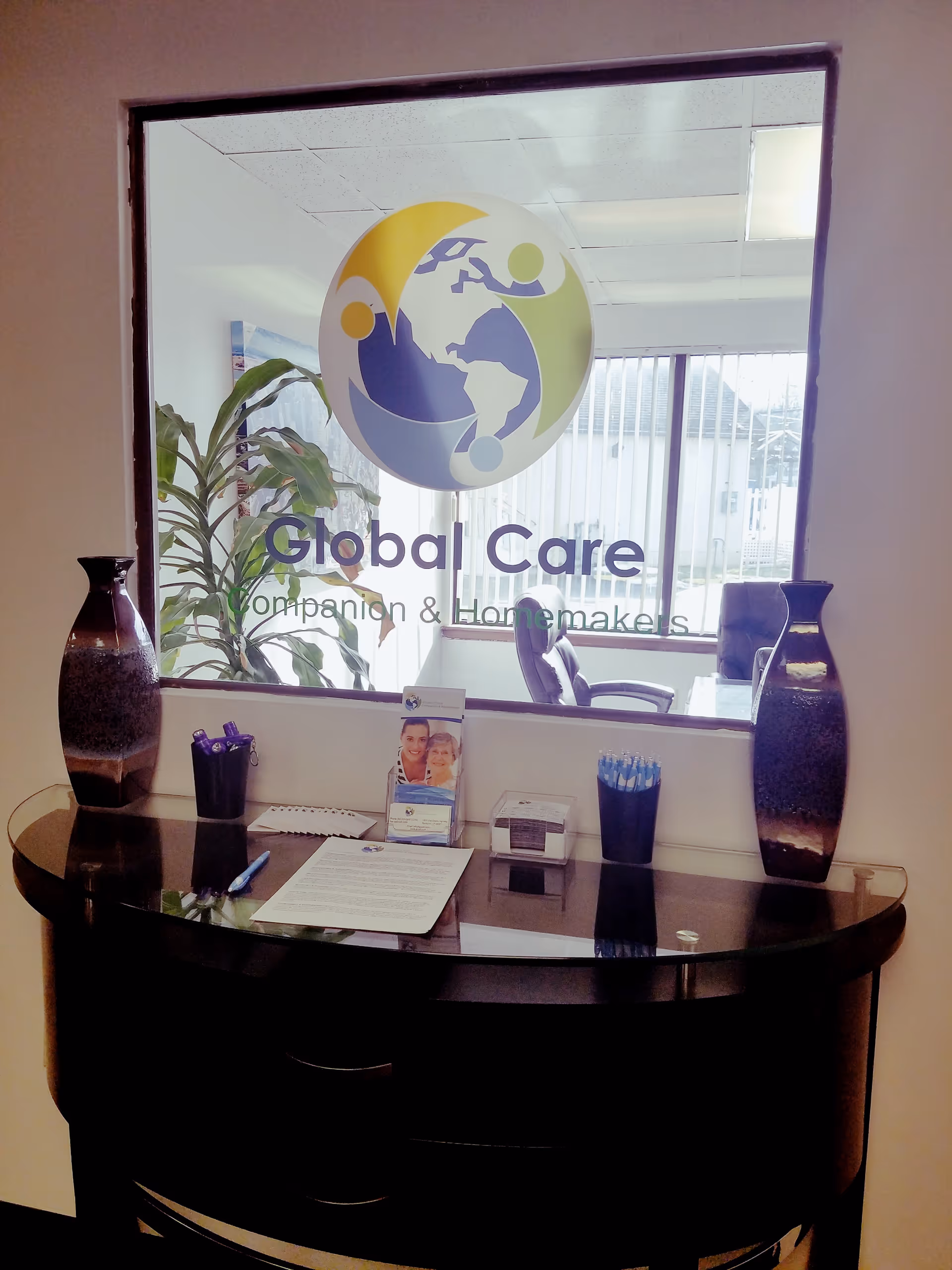 Reception desk inside a facility with a glass window logo reading Global Care Companion and Homemakers.