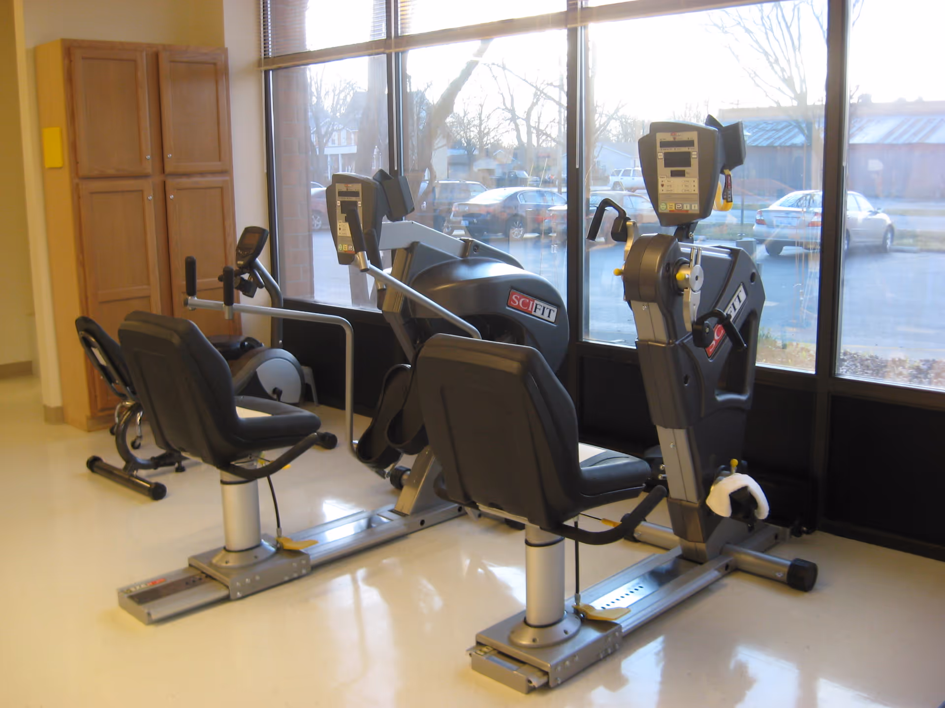 Senior fitness room with two stationary bikes near a large window and cabinets.