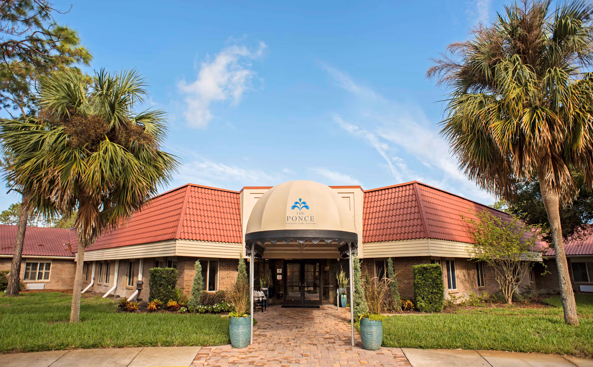 The Ponce Therapy Care Center entrance with curved canopy, brick building, and palm trees.