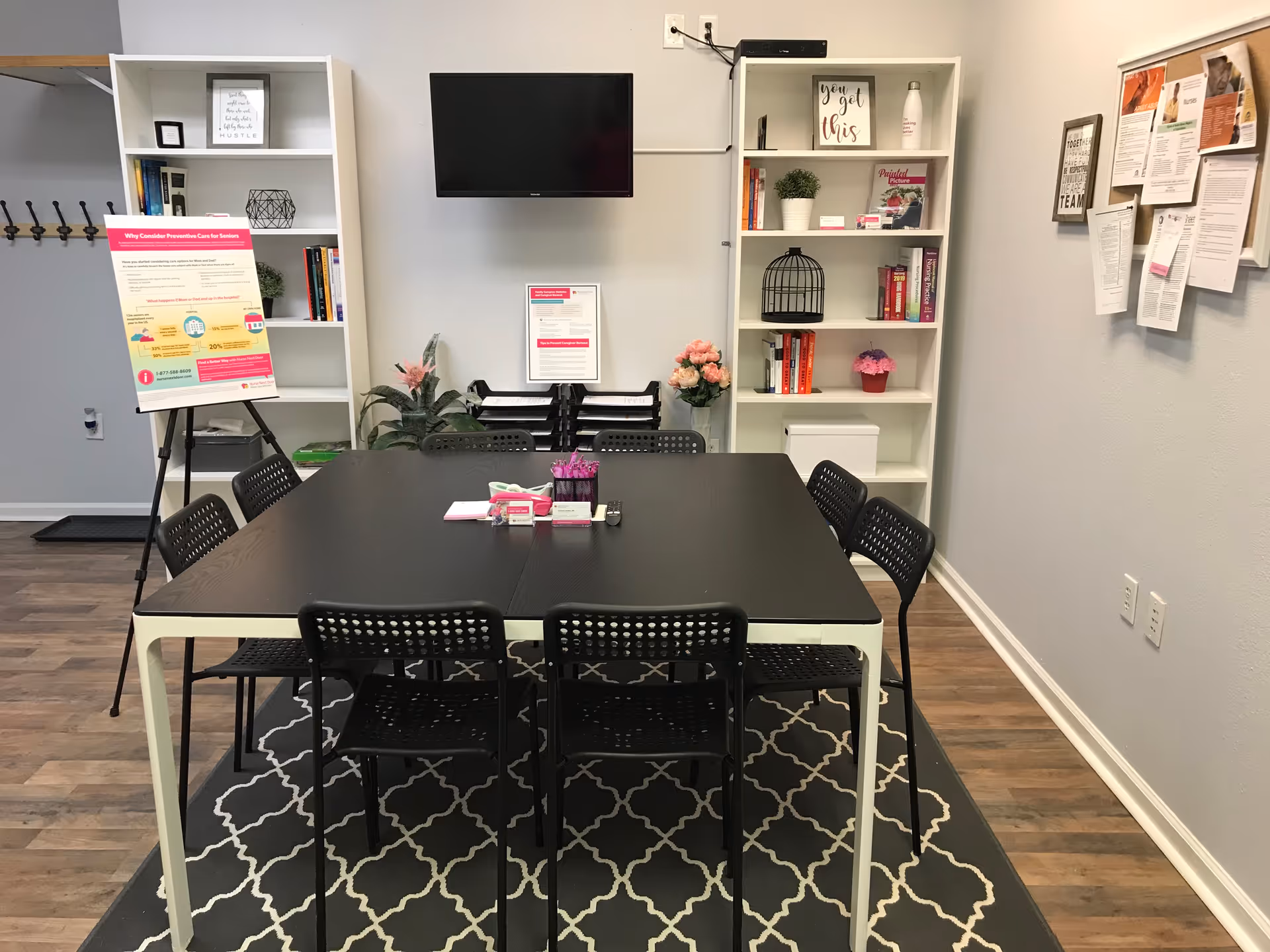 A modern meeting room with a dark table, black chairs, and bookshelves.