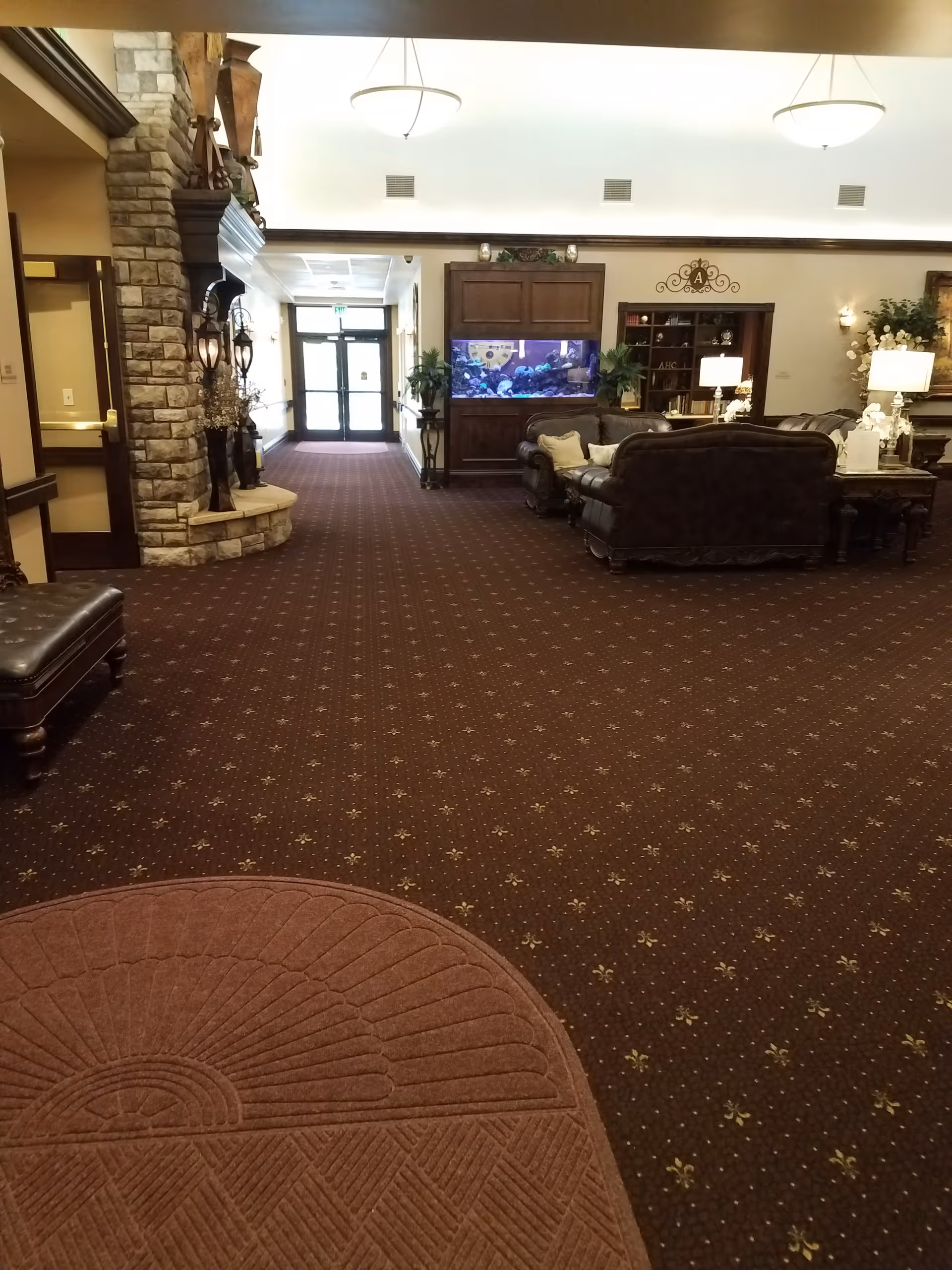 Elegant lobby area with dark wood furniture, leather seating, and a large aquarium TV.