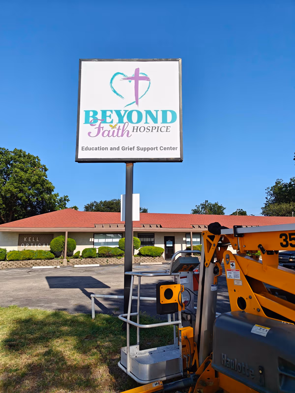 Outdoor view of Beyond Faith Hospice sign with building and equipment in the foreground.