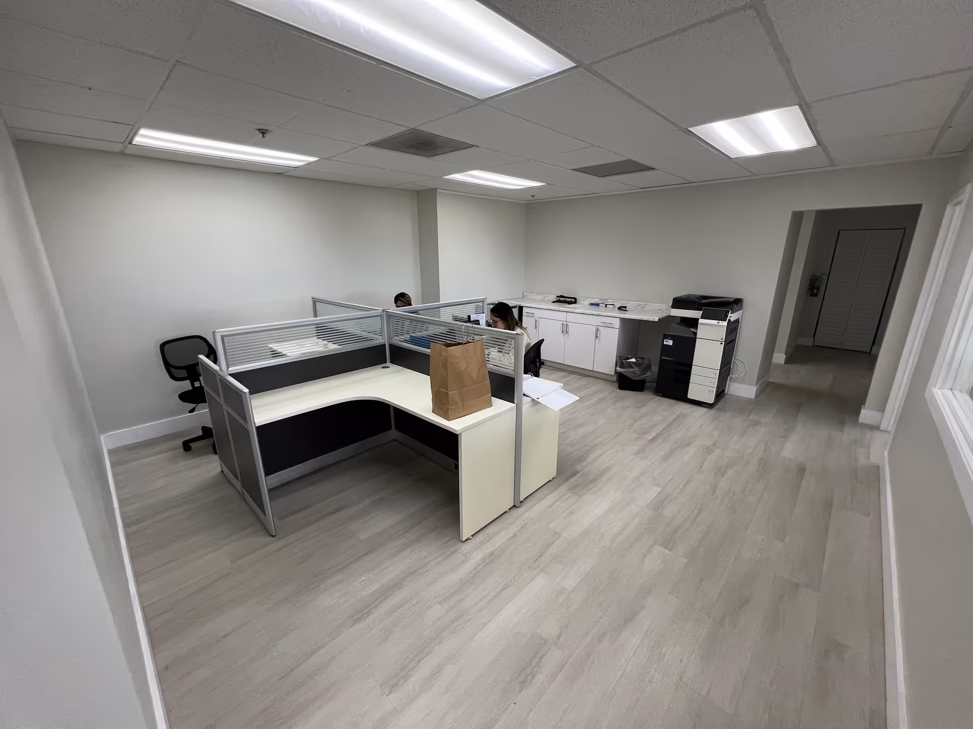 Interior office area with cubicles, a printer, and cabinets in a neutral, clean facility space.