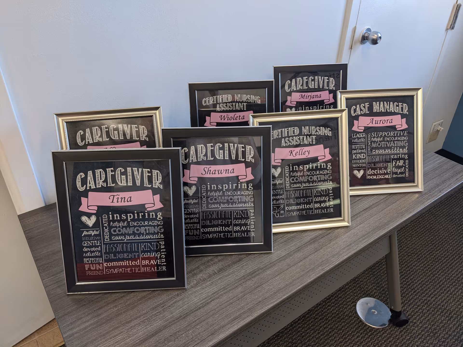Multiple framed caregiver plaques arranged on a table against a light wall.