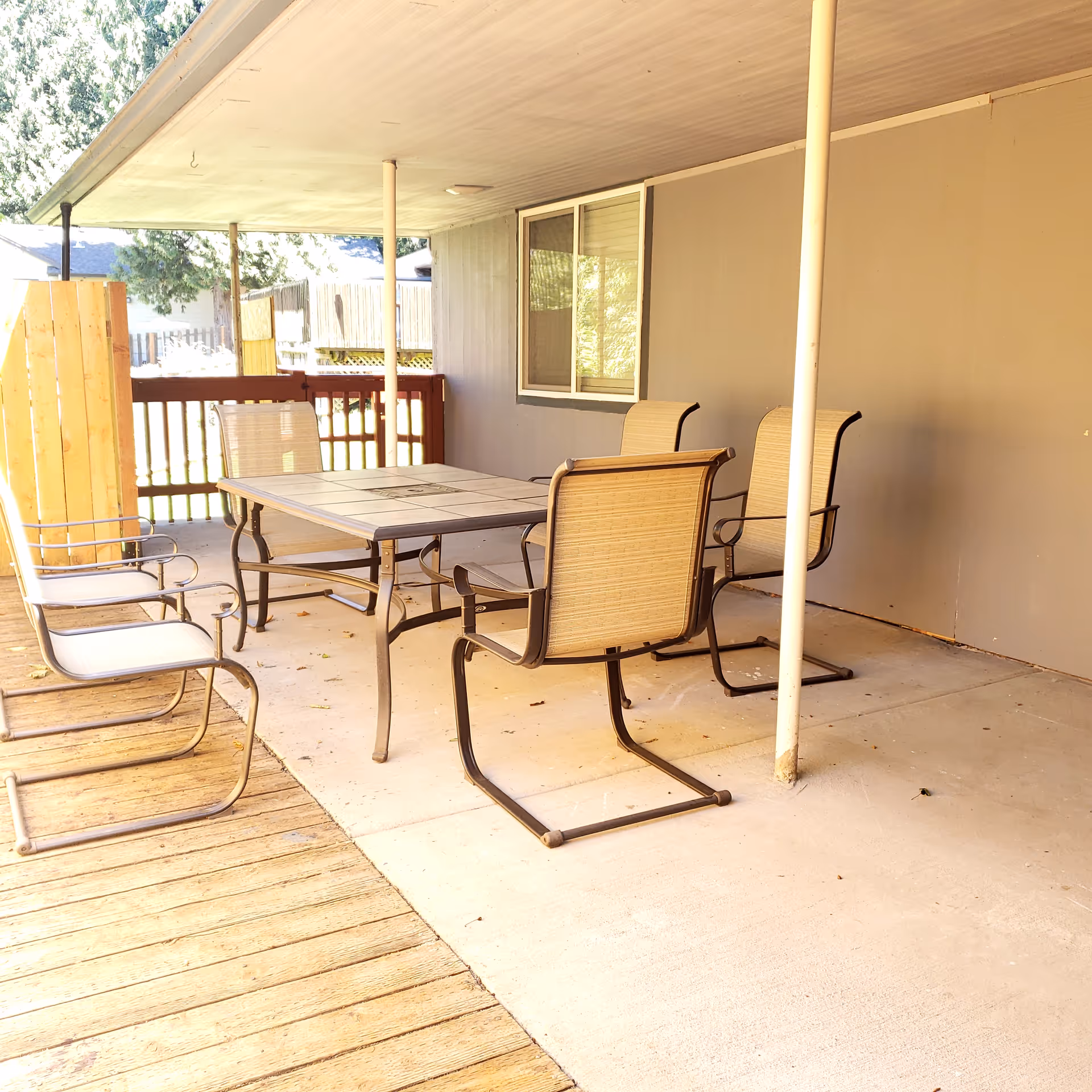 Outdoor covered patio with a tile-top table and metal chairs.