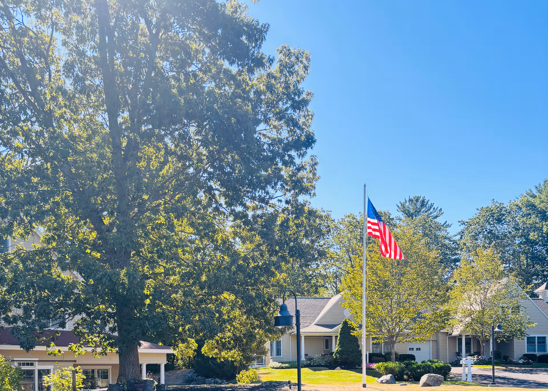 At Sentry Hill at York Harbor, a well-kept front exterior with trees, flagpole, and blue sky.