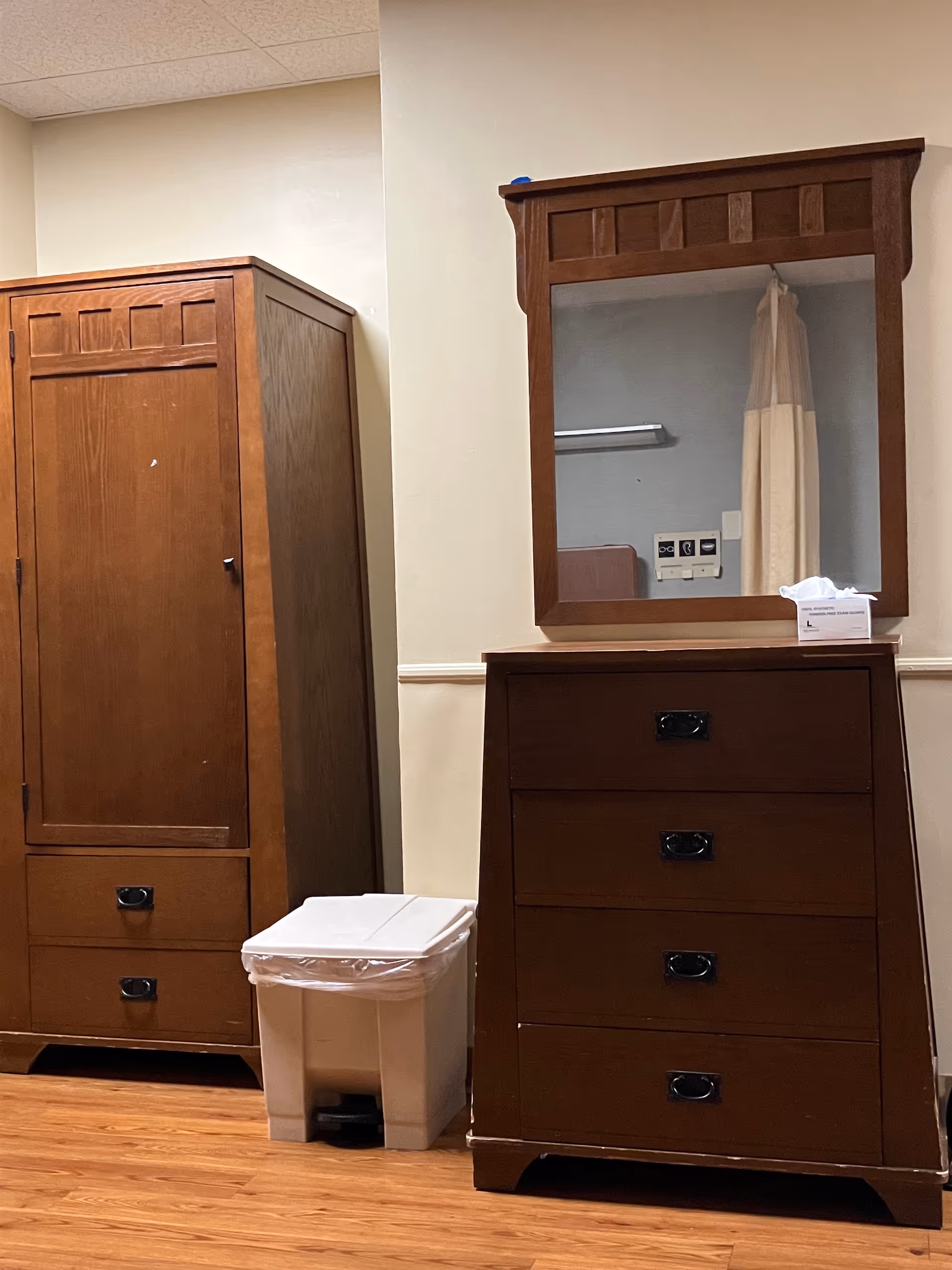 Wooden armoire and dresser with mirror in a furnished senior living room.