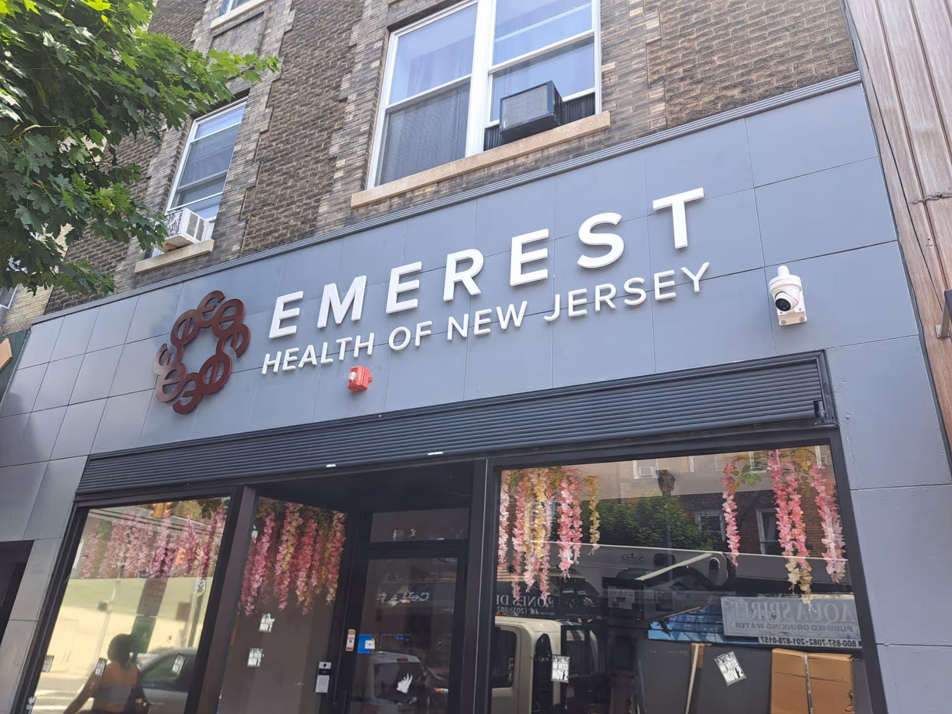 Exterior storefront displaying EMEREST HEALTH OF NEW JERSEY sign on brick building.