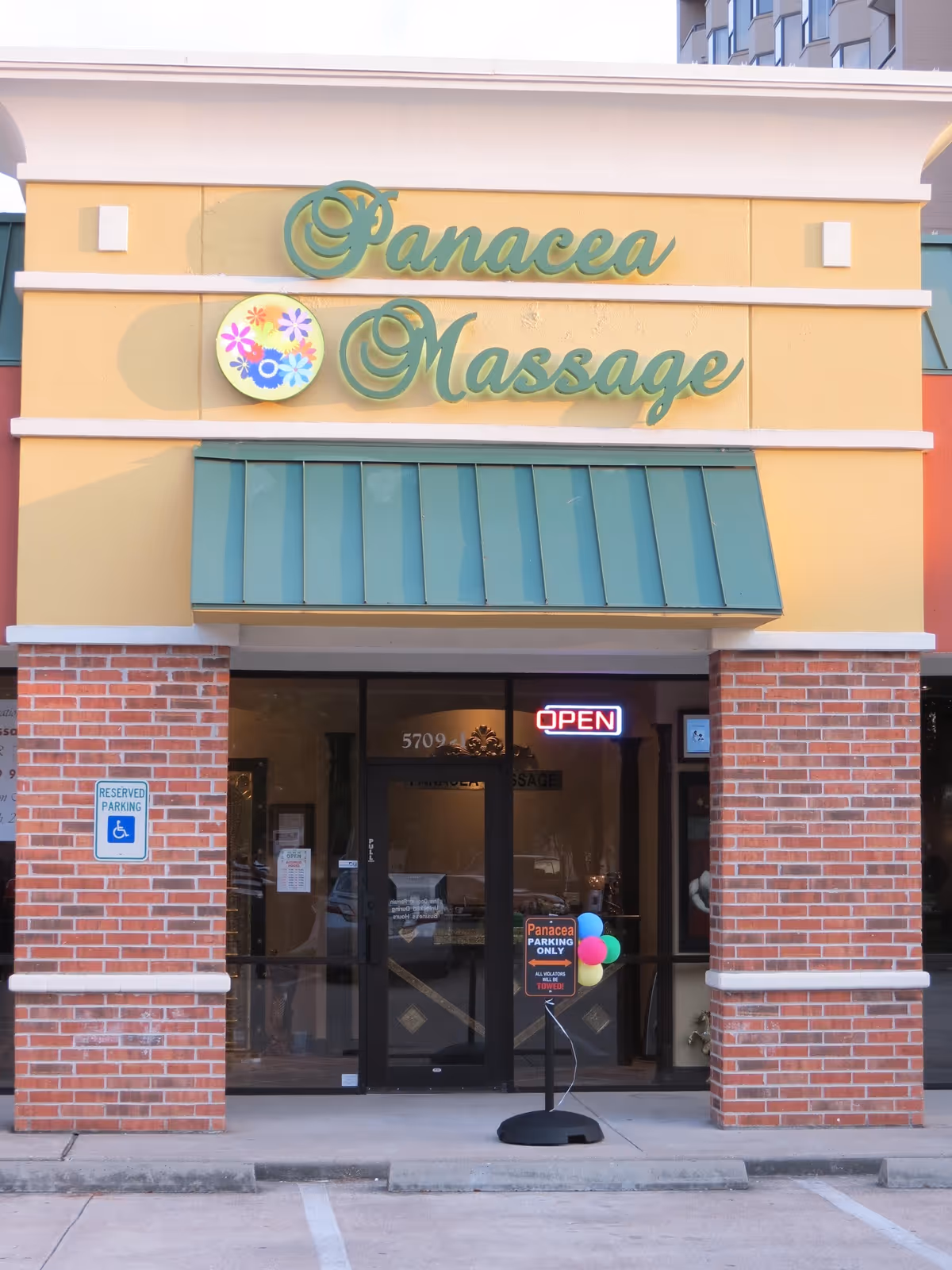 Front of Panacea Massage & Med Spa storefront with open sign and balloons.