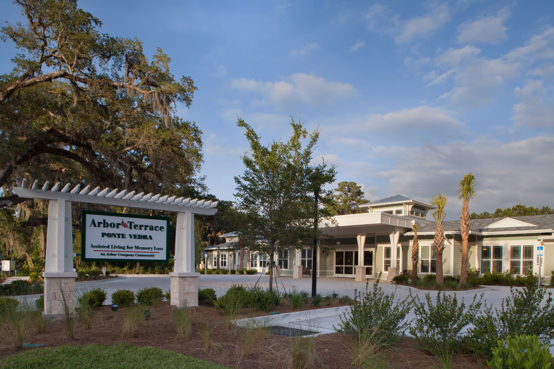 Front exterior of the Arbor Terrace Ponte Vedra assisted living facility showing the entrance, landscaping, and a large sign.