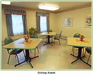 Bright dining room with several tables, chairs, blue curtains, and potted centerpieces.