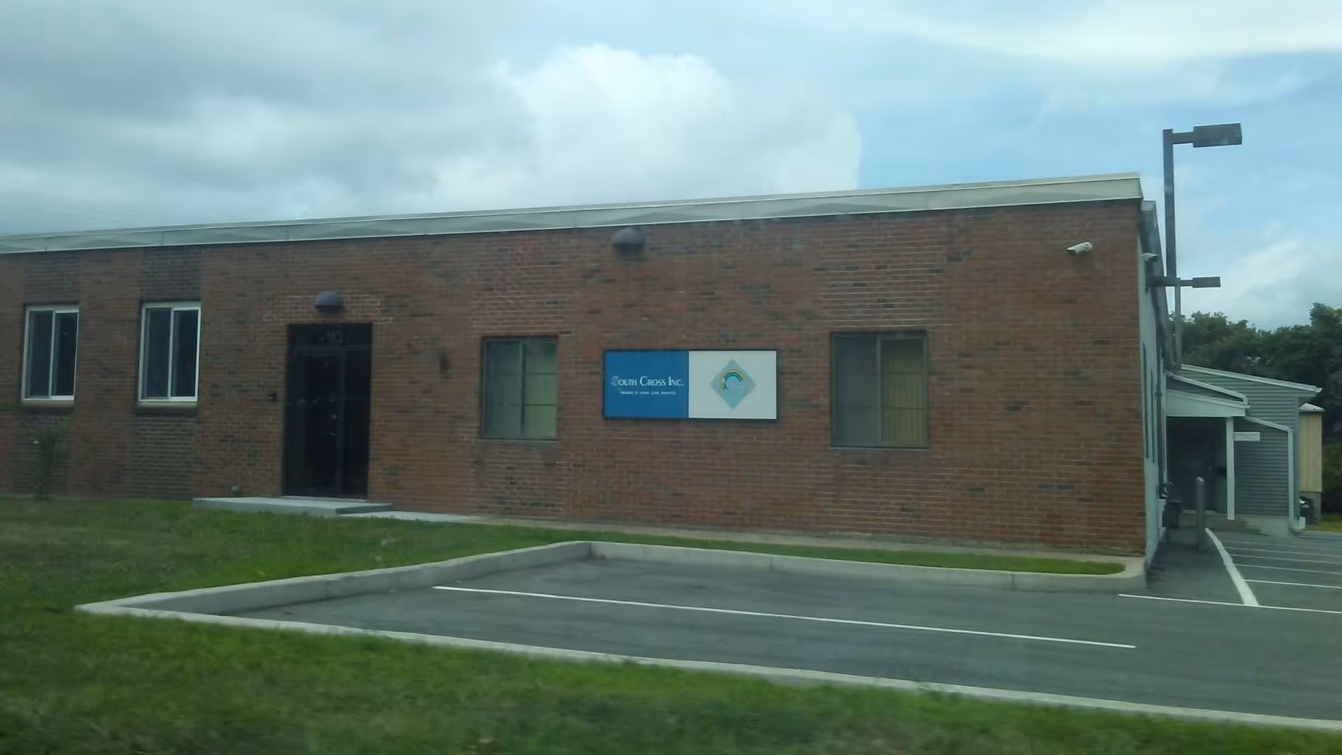 Exterior brick building labeled South Cross Inc. with a parking lot in front