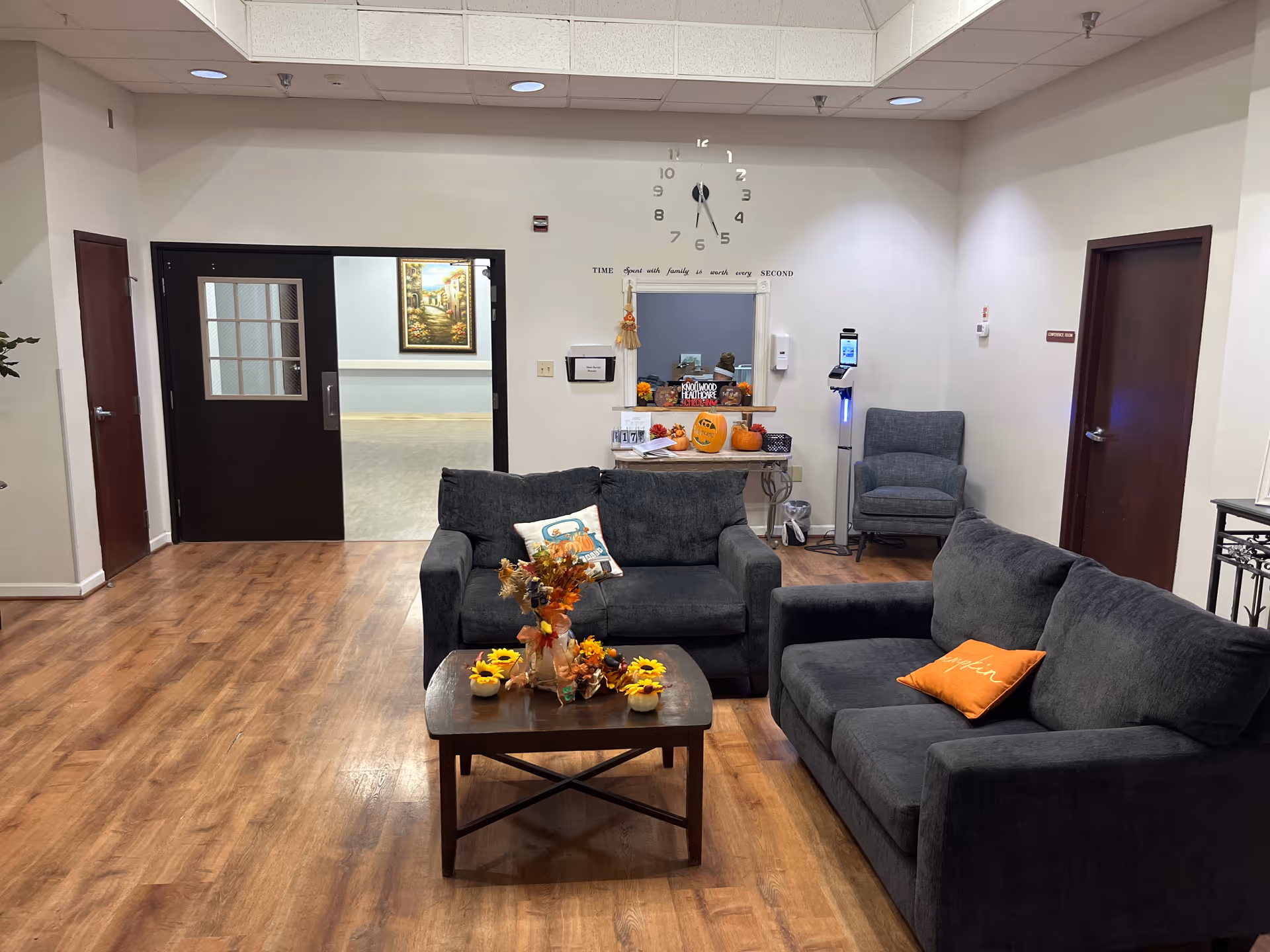 Cozy resident lounge with dark gray sofas, coffee table, and autumn decorations.
