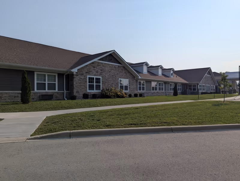 Exterior view of Rivercrest Senior Living building with brick and stone facade and front lawn